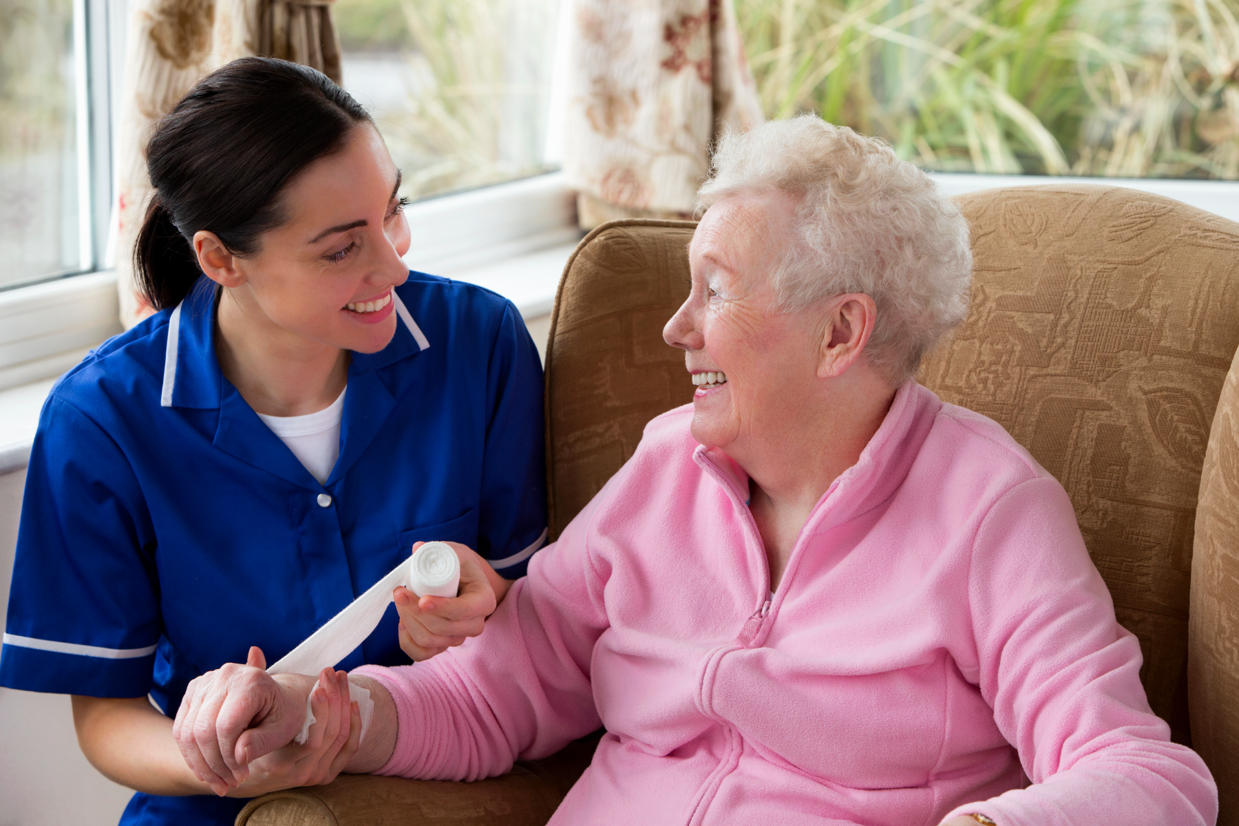 A nurse dressing an elderly woman's arm wound at home